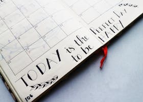 Open planner with handwritten quotes and calendar layout, promoting positivity and organization.